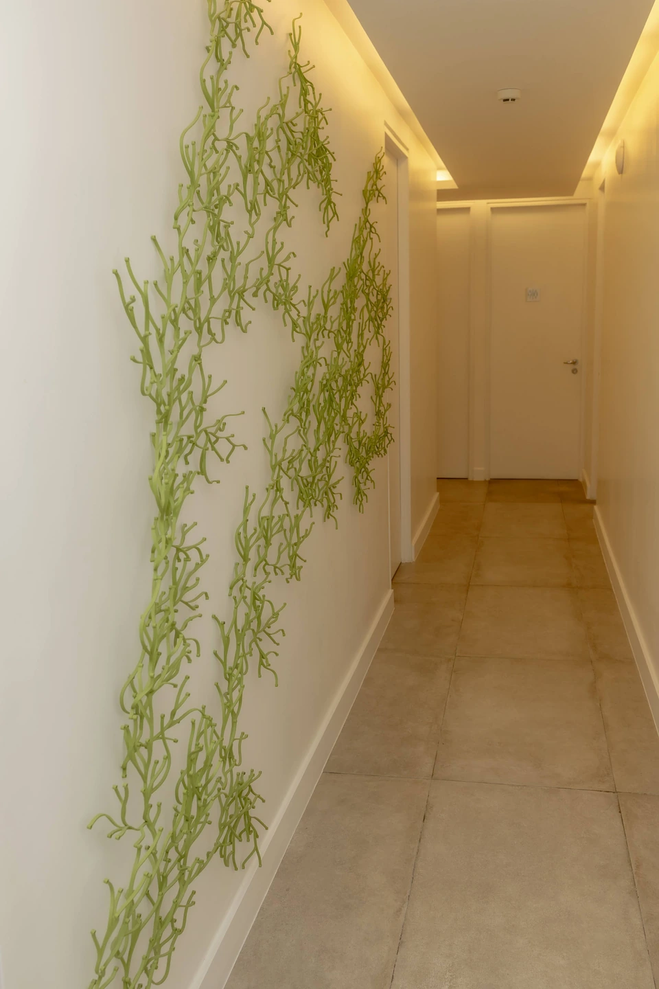 Corredor da Integer Clinic com arte verde na parede e iluminação acolhedora