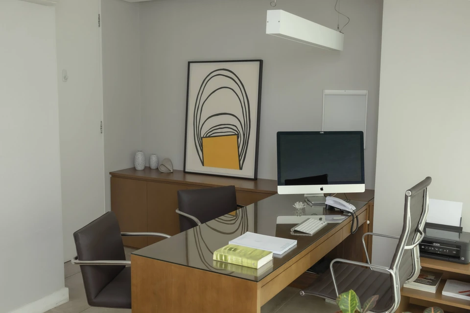 Consultório da Integer Clinic com mesa de vidro, cadeiras e quadro de formas orgânicas